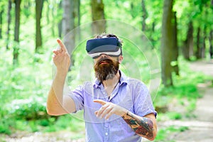 Hipster with mobile headset play on fresh air. Man with beard wear VR glasses on sunny outdoor. Bearded man with gadget