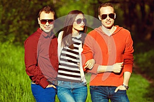 Hipster people concept. Portrait of fashionable friends in trendy casual clothing walking in the park together. Stylish eyewear.