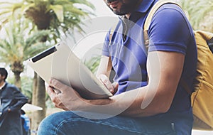 Hipster person holding in hands digital tablet with blank screen, man reading on computer on background nature park palm land