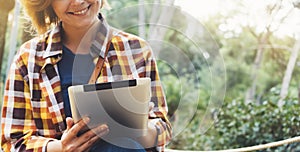 Hipster person holding in hands digital tablet with screen, young girl smile reading on computer on background nature park palm