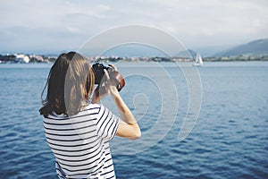 Hipster photograph on vintage camera or technology, mock up. Girl using vintage camerae on blue sea and yacht background close photo