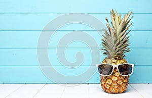 Hipster pineapple with sunglasses against blue wood