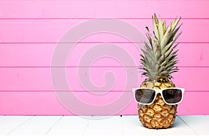 Hipster pineapple with sunglasses against pink wood