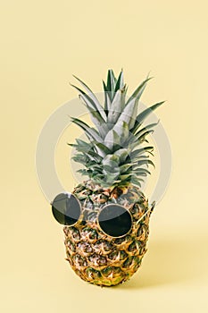 Hipster pineapple with sunglasses over pastel yellow background. Minimal creative concept