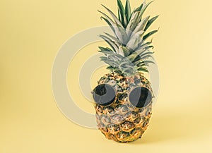 Hipster pineapple with sunglasses over pastel yellow background. Minimal creative concept