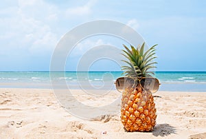 Hipster pineapple with sunglasses on tropical beach.