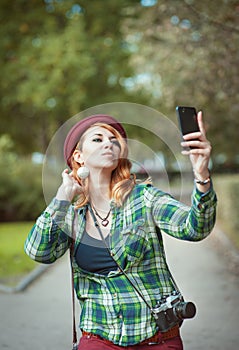 Hipster redhead woman in hat taking picture of herself