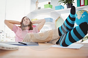 Hipster resting with legs on desk in office