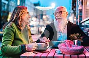 Hipster retired senior couple in love enjoying cappuccino at outdoor cafeteria - Joyful elderly lifestyle concept