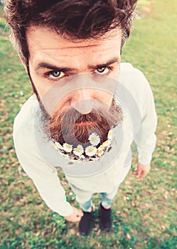 Hipster on serious face stand on grass, close up, defocused. Natural beauty concept. Man with beard and mustache enjoy