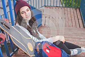 Hipster skateboarder girl with skateboard standing outdoor