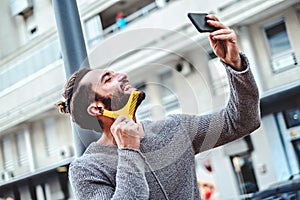 Hipster smiling nad combing beard in the street