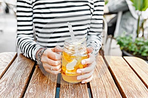 Hipster student drinks a cool lemonade through a straw in a summer outdoor cafe