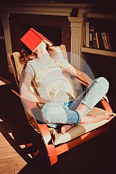 Hipster student napping in comfortable modern chair with paper book on face. Natural light. Bright sunny day. Knowledge and learni