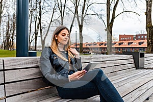 Hipster style young woman using tablet pc.caucasian woman entrepreneur working with modern pc tablet outdoors in spring at city