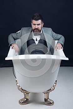 Hipster with stylish appearance in luxury old fashioned bathtub.