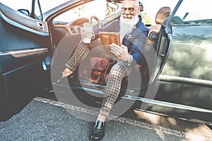 Hipster stylish man using tablet sitting inside convertible electric car - Senior entrepreneur having fun with technology trends