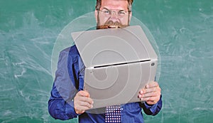 Hipster teacher wear eyeglasses and necktie bites laptop. Man hungry for knowledge. He needs new information. Thirst of