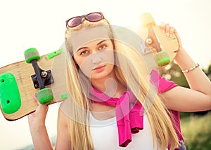 Hipster teenage girl with skateboard, image with sunflare