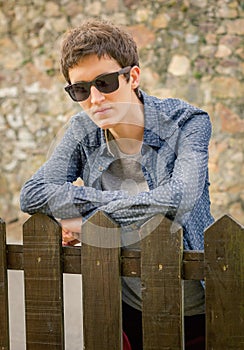 Hipster teenager with sunglasses over a fence