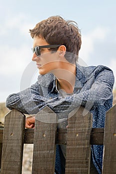 Hipster teenager with sunglasses over a fence