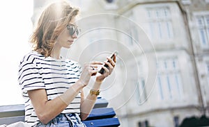 Hipster texting message on smartphone or technology, mock up of blank screen. Girl using cellphone on building castle background