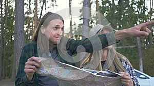 Hipster tourist couple in plaid shirts choosing the way to go on the background of forest