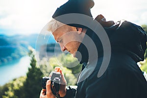 Hipster tourist hold in hands taking photography click on retro vintage photo camera in auto, photographer looking on camera