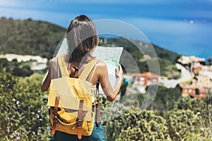 Hipster tourist hold and look map on trip, lifestyle concept adventure, traveler with backpack on background mountain and blue sea