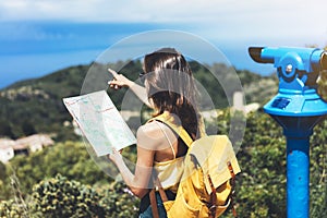 Hipster tourist hold and look map on trip, lifestyle concept adventure, traveler with backpack on background mountain and blue sea