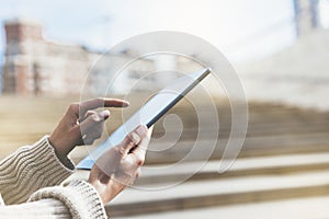 Hipster tourist texting message on tablet or technology mock up. Person using computer on building background close. Female hands