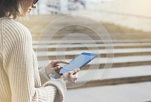 Hipster tourist texting message on tablet or technology mock up. Person using computer on building background close. Female hands