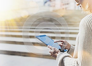 Hipster tourist texting message on tablet or technology mock up. Person using computer on building background close. Female hands