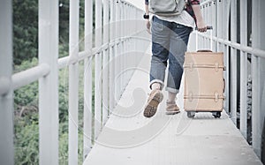 Hipster travel woman drag vintage luggage on bridge