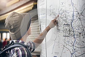 Hipster traveler with backpack pointing at city map