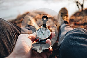 Hipster traveler hold vintage compass in hand on background of him legs in hiking boots