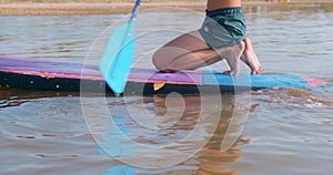 Hipster walks on sup board in the lake.