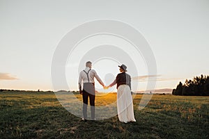 Hipster wedding couple kissing on a field in sunset light in fog