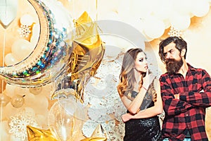 Hipster and woman on new year or xmas eve. Sensual woman and bearded man with party balloons, christmas. Couple in love