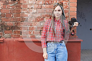Hipster woman photographer with retro film camera on old brick wall