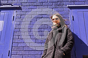 Hipster woman with sunglasses standing in front of violet wall