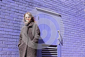 Hipster woman with sunglasses standing in front of violet wall