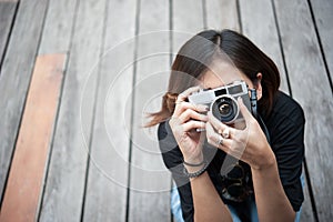 Hipster woman taking photos with retro film camera on wooden floorof city park,beautiful girl photographed in the old camera