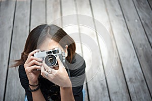 Hipster woman taking photos with retro film camera on wooden floorof city park,beautiful girl photographed in the old camera