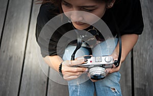 Hipster woman taking photos with retro film camera on wooden floorof city park,beautiful girl photographed in the old camera