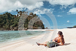 Hipster woman traveler with backpack on the coast enjoying island view.