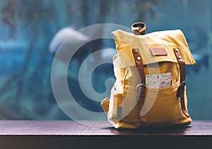 Hipster yellow backpack and map closeup. View from front tourist traveler bag on background blue sea aquarium. Person hiker visiti