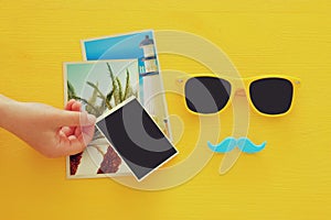 Hipster yellow sunglasses and funny moustache next to blank photographs