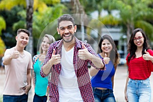 Hipster young adult with beard showing thumb up with group of friends