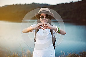 Hipster young asian woman showing hands heart shape at nature sunset,Travel insurance concept